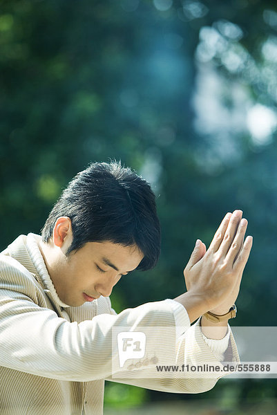 Mann hält Hände im Gebet und neigt sich dem Kopf.