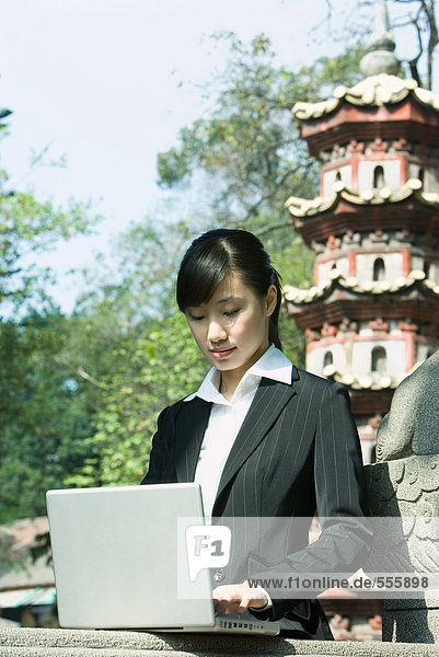 Woman using laptop  pagoda in background