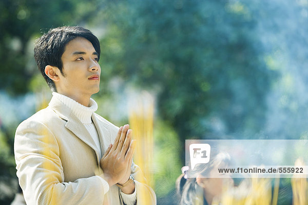 Man praying  incense burning in foreground