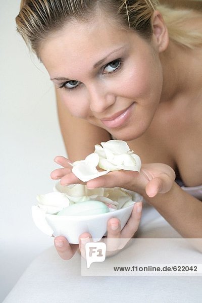 Portrait of young woman holding bowl of flower petals and smiling