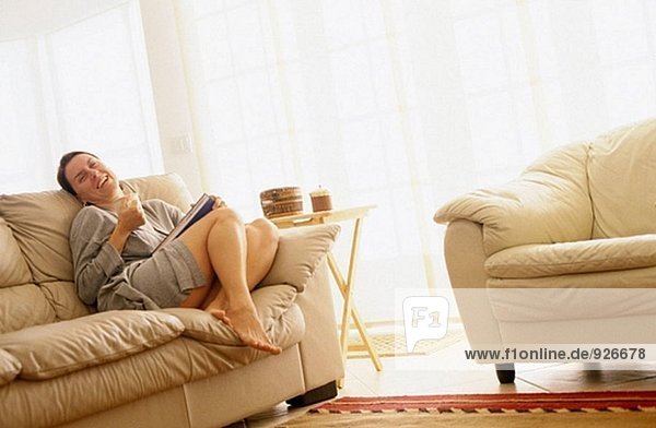 Frau auf dem Sofa mit Buch und eine Tasse Kaffee