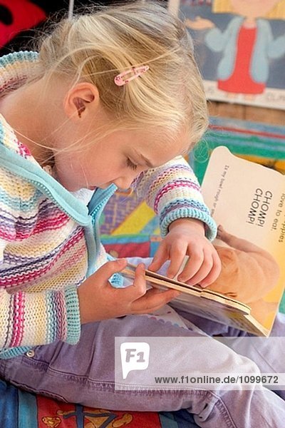 Vier Jahre altes Mädchen Konzentration auf lesen ein Buch in der Nursrey Schule
