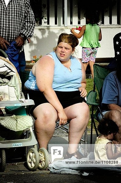Young fettleibige Frau sitzt auf Stuhl beim Anschauen einer parade