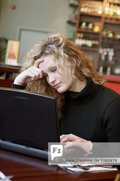 20 Jahre altes Mädchen in einer Bar auf einem Laptop arbeiten.