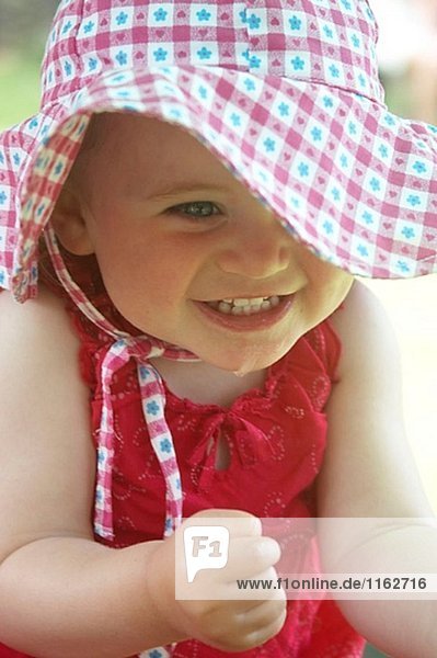 18 Monate altes Mädchen außerhalb in großen floppy Hut  Hände Klammer-ihr zusammen in Aufregung.