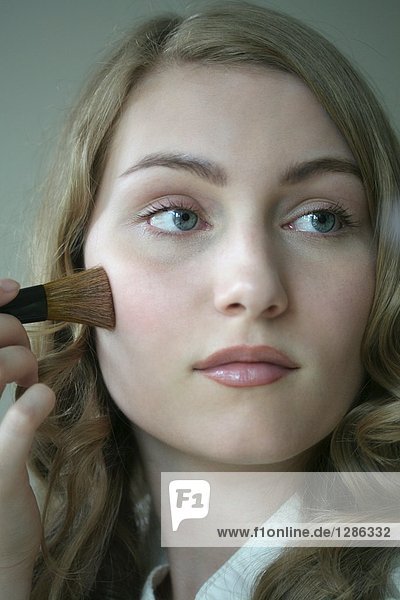 Young woman powdering face
