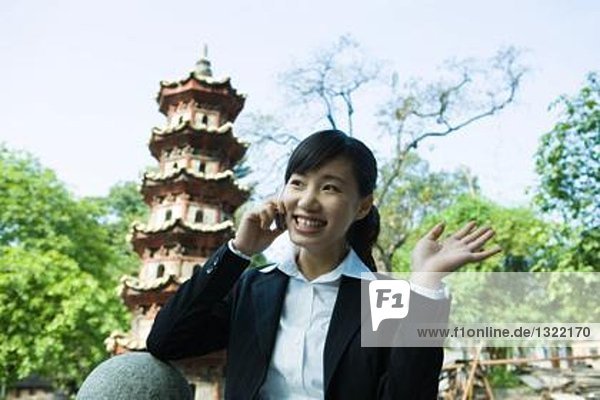 Young woman using cell phone  pagoda in background