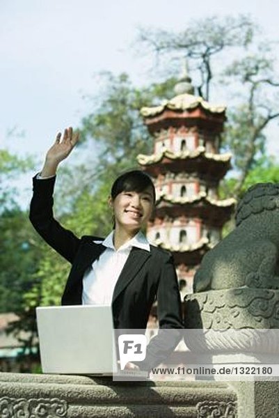 Young woman using laptop  waving