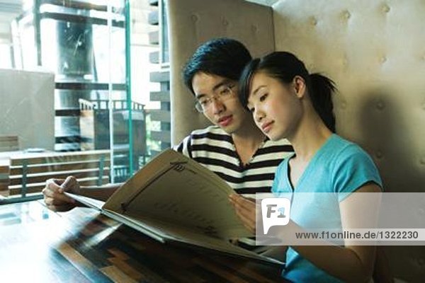 Young couple sitting in restaurant  holding menu
