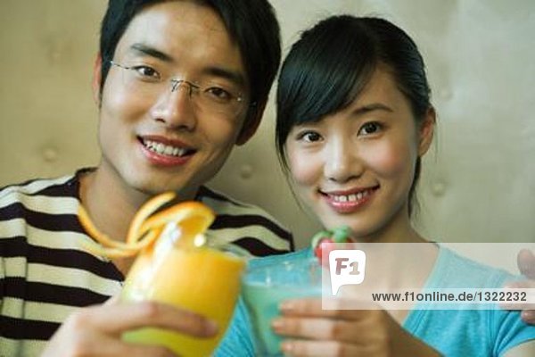 Young couple holding cocktails  clinking glasses