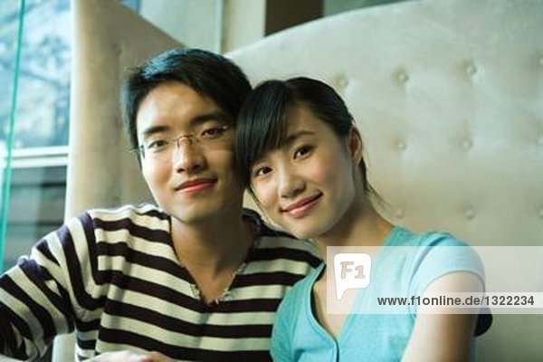 Young couple sitting in booth  smiling at camera