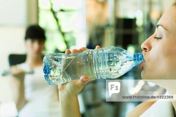 Zwei Frauen im Kraftraum  Schwerpunkt Frau im Vordergrund Trinkflasche Wasser