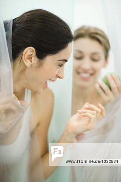 Frau überreicht Freundin Seife in öffentlichen Duschen