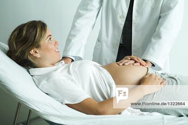 Pregnant woman lying on back  doctor's hand on stomach