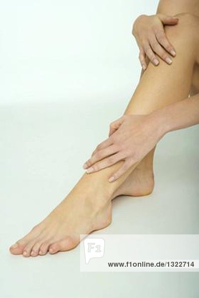 Frau berührt die Beine  Nahaufnahme  Ausschnitt vom Knie abwärts