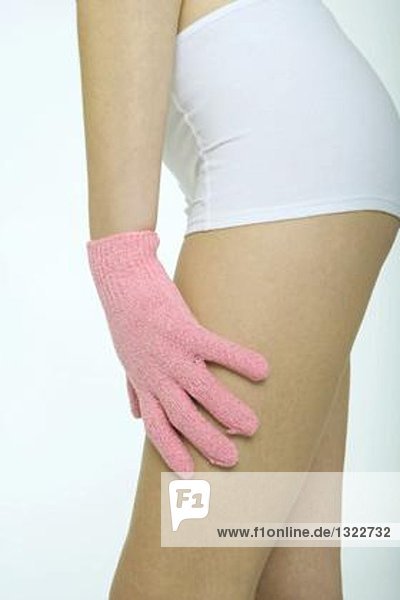 Junge Frau berührt Bein mit Massagehandschuh  Nahaufnahme des Mittelteils