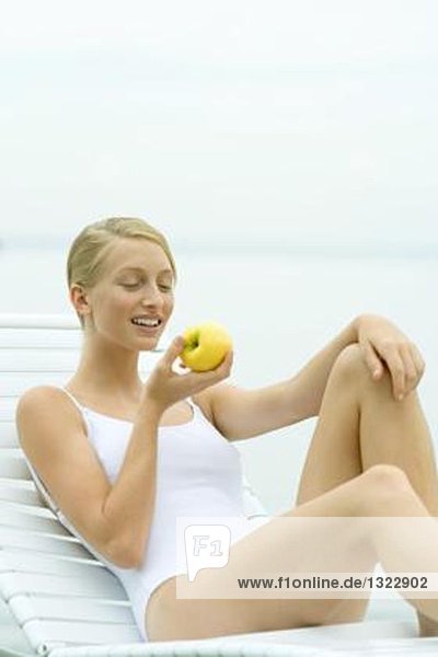 Teenagermädchen im Badeanzug  im Sessel sitzend  Apfel essend