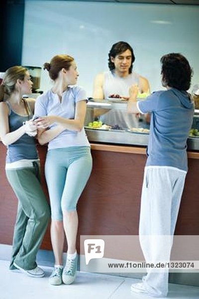 Junge Erwachsene in Sportbekleidung  Pause in der Cafeteria des Fitnessclubs