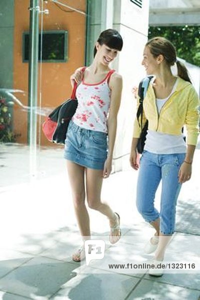 Young women walking on sidewalk in street clothes