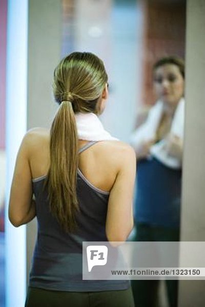 Young woman looking at self in mirror  rear view