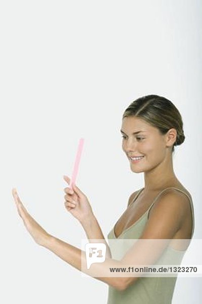 Young woman holding nail file  admiring nails