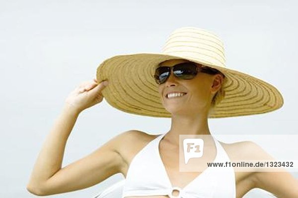 Junge Frau mit Sonnenbrille und Sonnenhut  Kopf und Schultern
