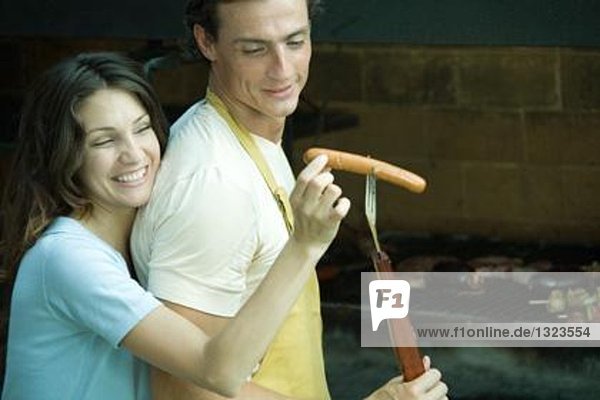 Paar beim Kochen  Frau nimmt Hotdog aus der Gabel des Mannes