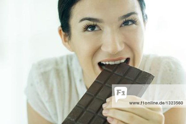 Frau beißt aus der Tafel Schokolade