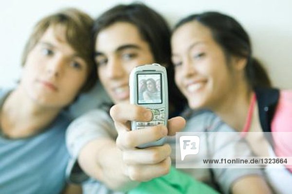 Teenager-Freunde fotografieren mit dem Handy  Fokus auf das Telefon im Vordergrund