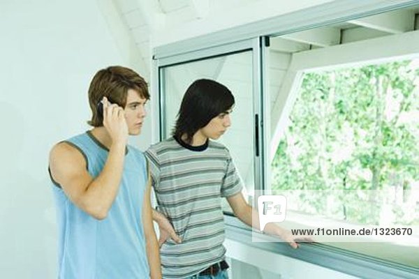 Teenager-Freunde stehen am Fenster,  einer mit Laptop