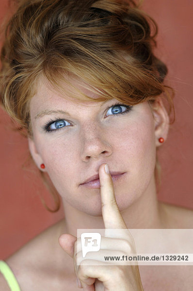 Junge Frau hält Finger auf den Lippen  Nahaufnahme
