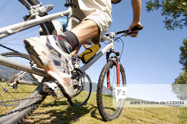 Young man riding mountain bike  low angle view  low section