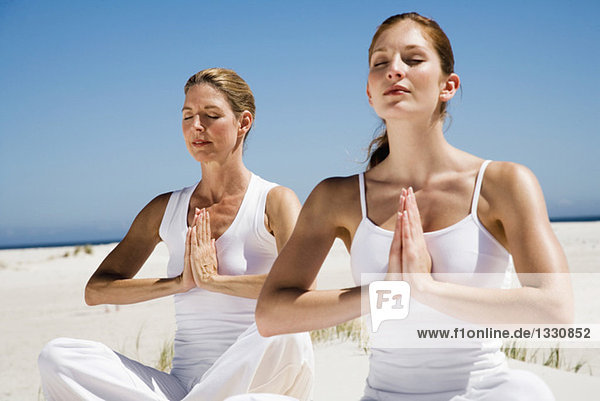 Zwei Frauen beim Yoga am Strand