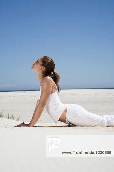 Junge Frau beim Yoga am Strand