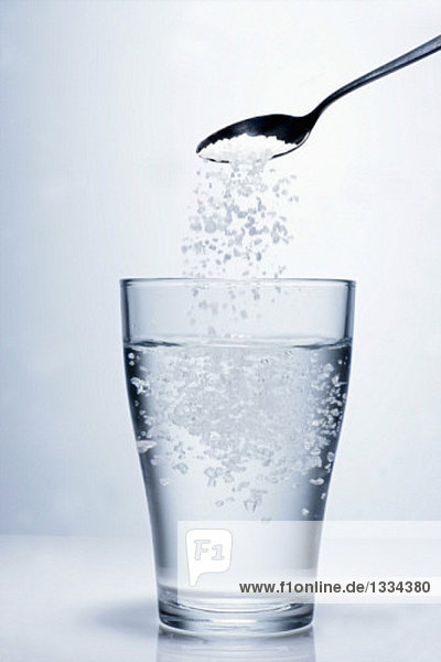 Salz in ein Glas Wasser schütten