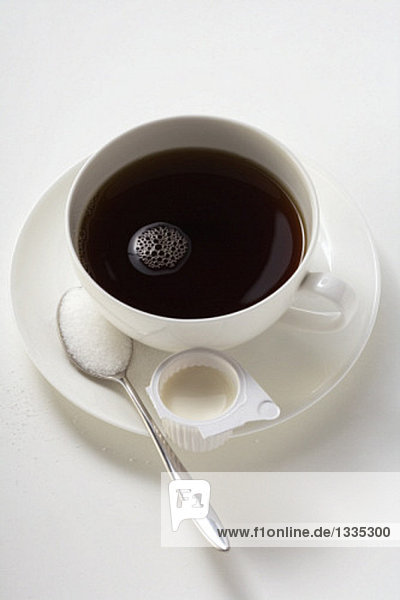 Eine Tasse Kaffee mit Milch und Zucker