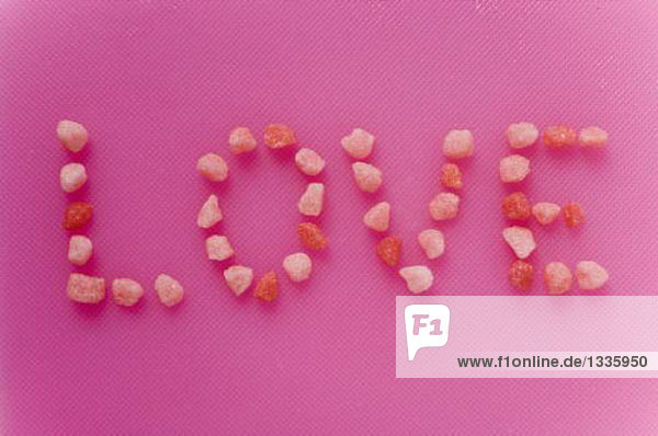 Schriftzug Love aus kleinen rosa Zuckerbonbons