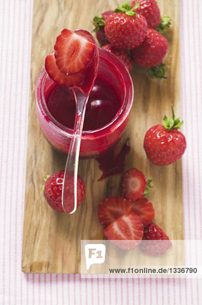 Glas Erdbeermarmelade und frische Erdbeeren auf Schneidebrett