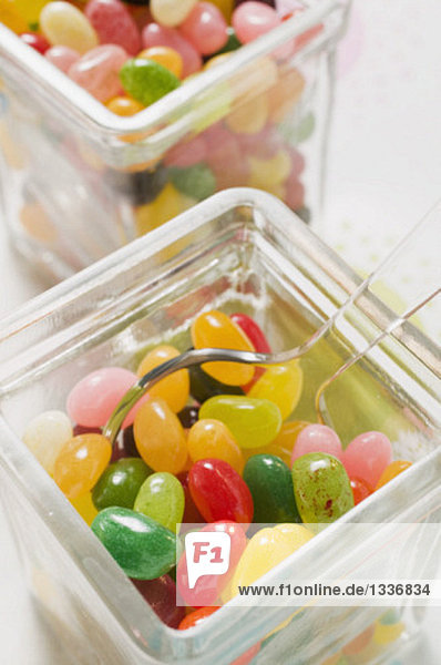 Coloured jelly beans in two storage jars (close-up)