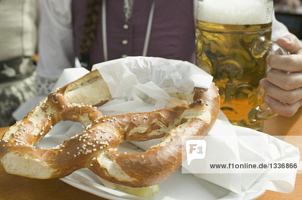 Frau mit Mass Bier und Brezel beim Oktoberfest