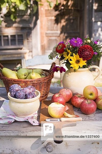 Ländliches Obststilleben auf Gartentisch vor Bauernhaus