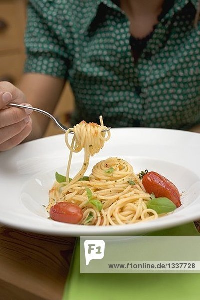 Woman behind plate of spaghetti with tomatoes and basil