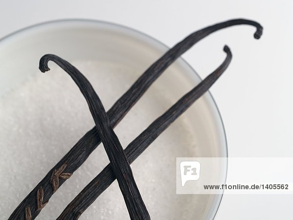 High angle view of vanilla sticks and sugar in bowl