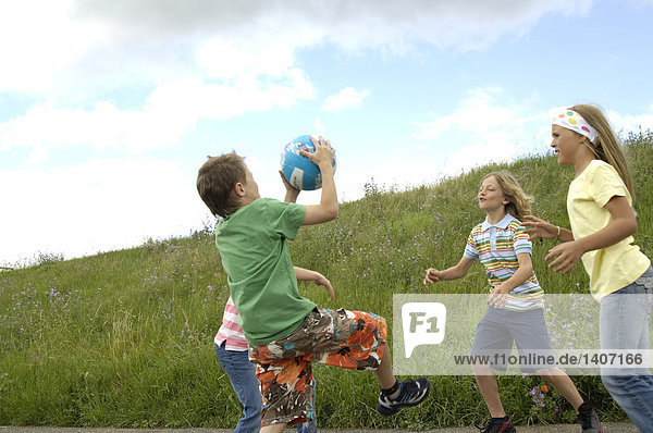 Vier Kinder spielen mit Ball im Feld