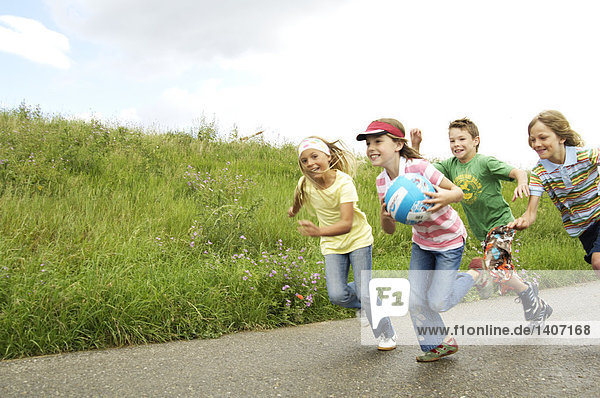 Three children chasing girl holding ball