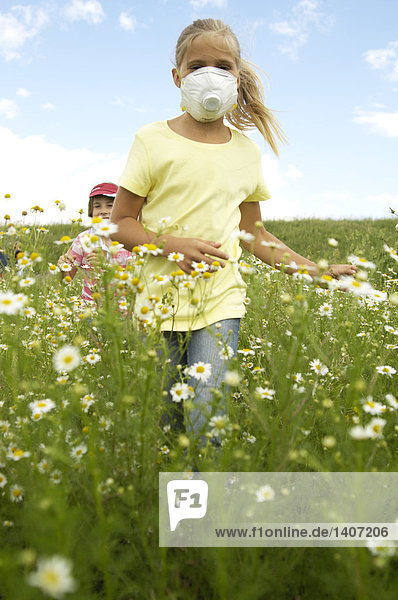 Mädchen jagen ihre Freundin mit op-Maske im Feld