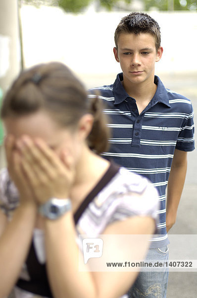 Close-up of teenage girl sobbing with her friend standing in background