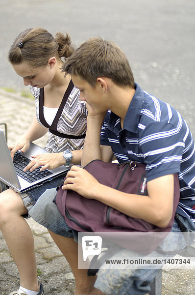 Teenagerin mit Laptop mit ihrer Freundin sitzen neben ihr