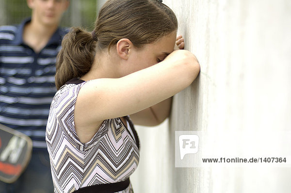 Seitenprofil Teenagerin Schluchzen gegen Wand mit ihrer Freundin im Hintergrund
