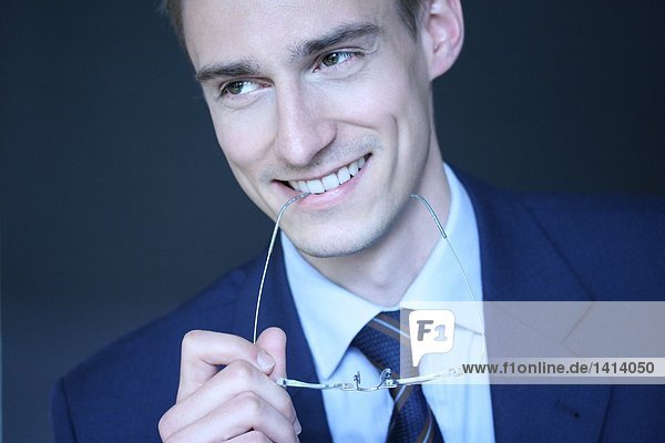 Close-up of businessman smiling and holding eyeglasses